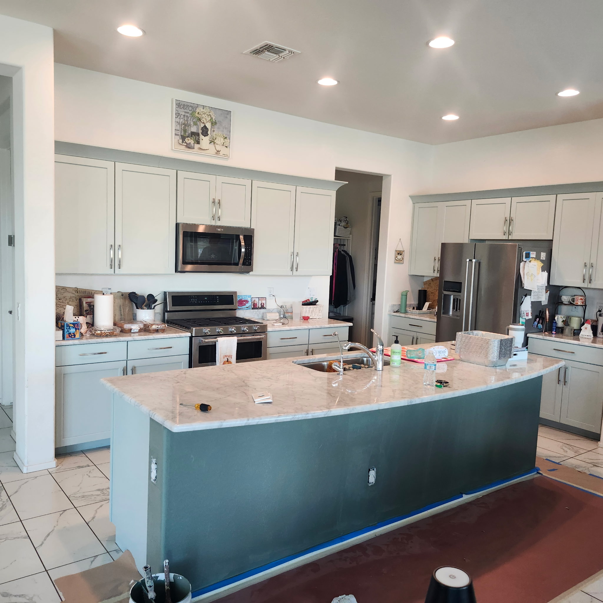 Kitchen cabinet repaint in progress with sage cabinets and navy island