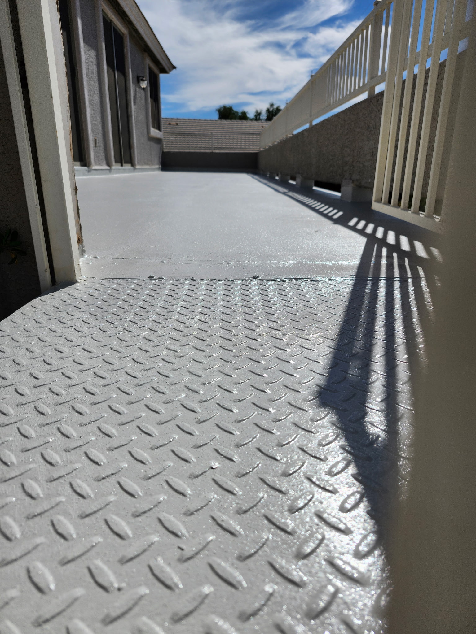 Diamond-plate textured coating on an upper balcony deck, gray finish